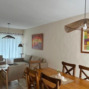 A dining area with a wooden table and chairs, a sofa, and a painting on the wall. - Alojamiento Carilo Princes (Carilo)
