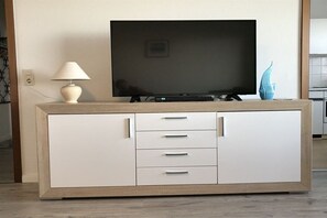 A television on a cabinet with drawers and a lamp beside it. - Apartment with a view of the islands (Wittdün \/ Amrum)