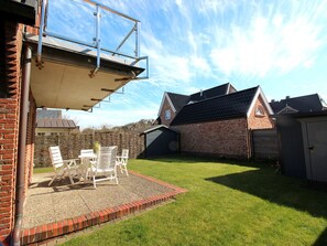 A backyard with a patio, a brick wall, and a shed. - Holiday Home With 2 Bedrooms (Sylt)