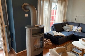 A living room with a modern fireplace, a dark blue sofa, and a small round table. - Holiday apartment in Ahaus with swimming pool (Ahaus)