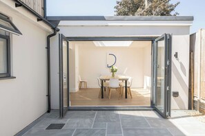A modern patio with a glass door leading to an indoor dining area. - Lantern House | Historic Wells | Sleeps 11 (Somerset)