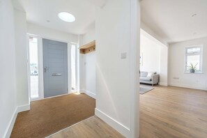 A modern interior with a wooden floor, a grey door, and a white wall with a light switch. - Lantern House | Historic Wells | Sleeps 11 (Somerset)