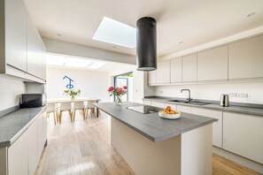 Una cocina moderna con una isla central, un comedor con sillas y vistas al exterior.