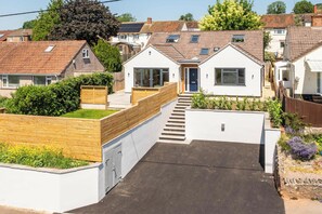A residential property with a front garden, a wooden fence, and a pathway leading to the entrance. - Lantern House | Historic Wells | Sleeps 11 (Somerset)