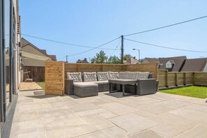 Eine Außenpatio-Terrasse mit einer Eckcouch und einem Tisch.