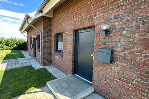A brick building with a black door, a small window, and a mailbox on the side. - Holiday home with 2 bedrooms (Friedrichskoog-Spitze)