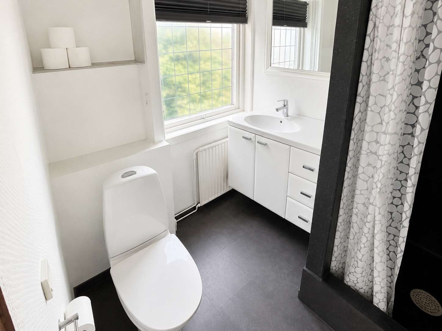 Un baño moderno con inodoro, lavamanos y ventana.
