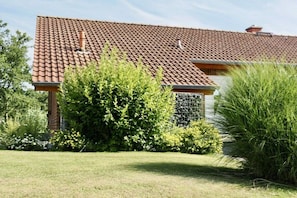 Ein Haus mit Ziegeldach, umgeben von Grünflächen und einem gepflegten Rasen.