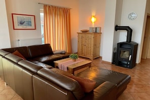 Ein Wohnzimmer mit einer Couch, einem Holzschrank, einem Tisch mit Pflanze, einem Kamin und einem gerahmten Bild an der Wand.