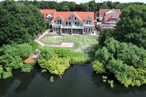 A large house with a red roof, surrounded by dense greenery and a body of water. - Holiday apartment with 1 bedroom (Norddeich)