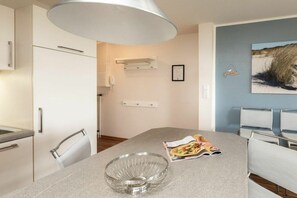 A modern kitchen with a large island, white cabinets, and a dining area with chairs. - "Waddensee" at Uns to Hus (Juist)