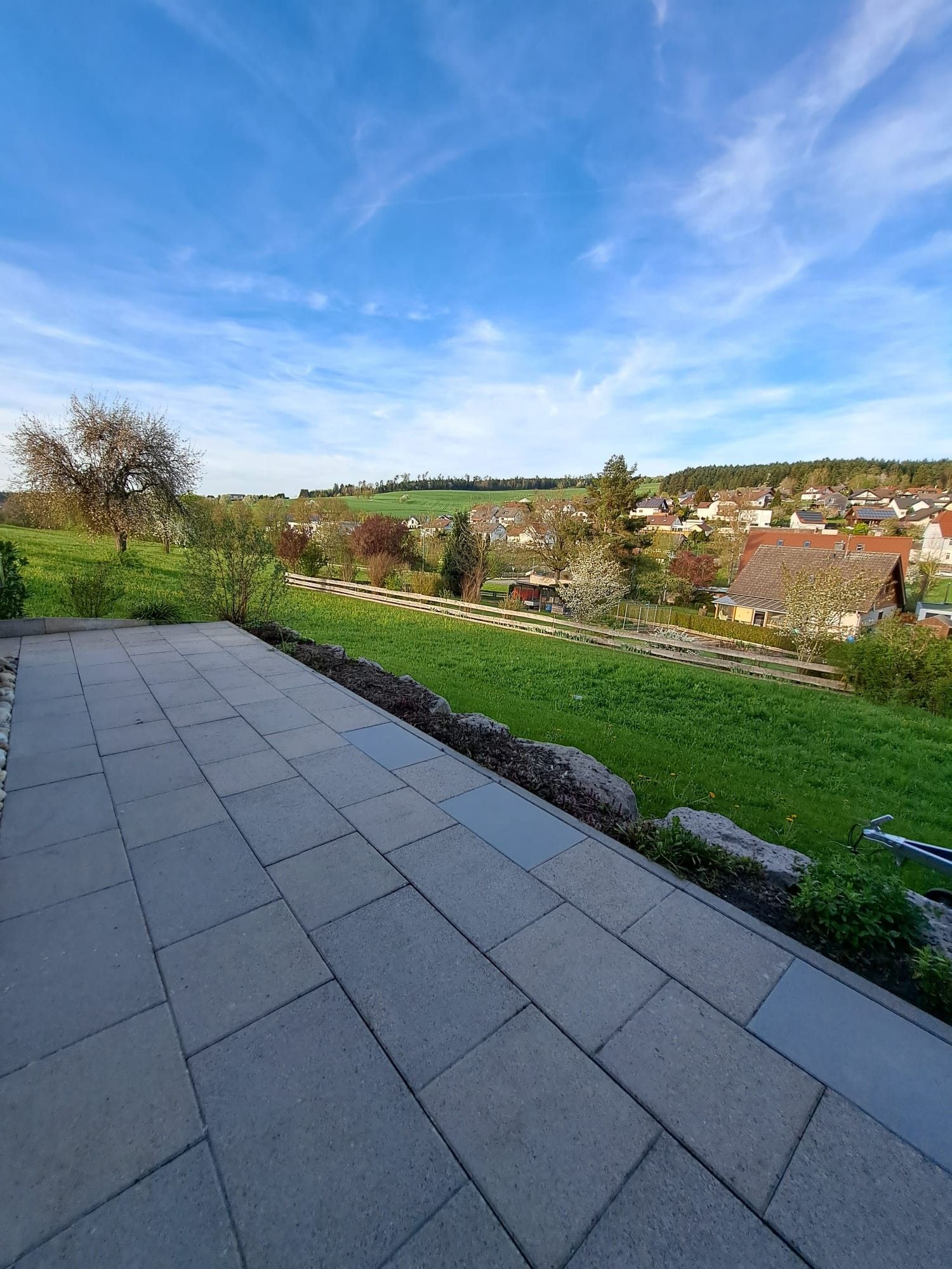 Ein gepflasterter Außenbereich mit Blick auf ein Wohngebiet und einem klaren Himmel.
