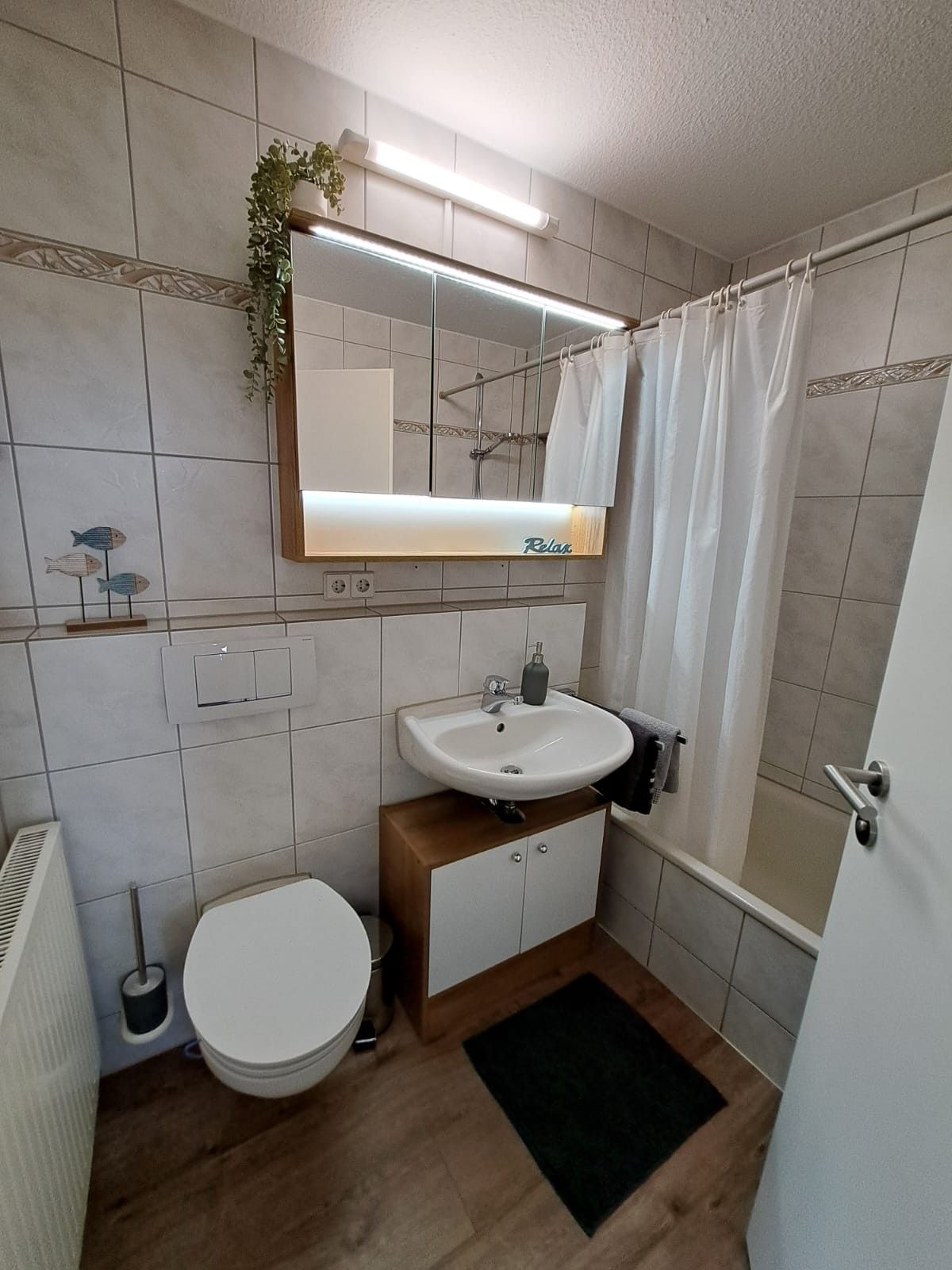Un baño con inodoro, lavamanos y zona de ducha.