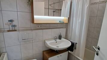 Un baño con inodoro, lavamanos y zona de ducha.