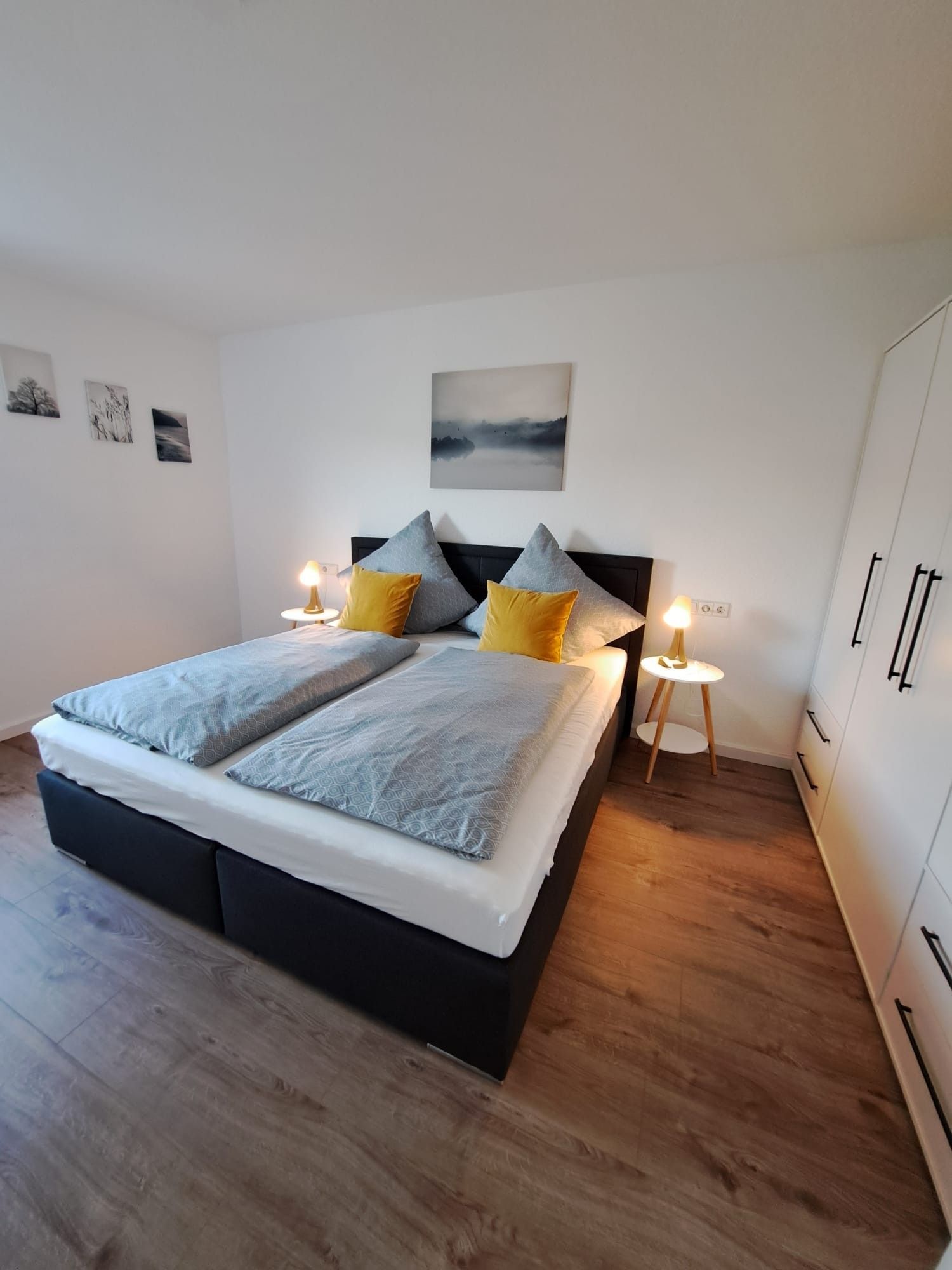A modern bedroom with a large bed, two bedside lamps, and a view of the sky through the window.