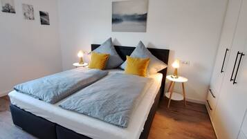 A modern bedroom with a large bed, two bedside lamps, and a view of the sky through the window.