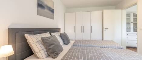 A bedroom with a bed, bedside table, lamp, and a wardrobe.