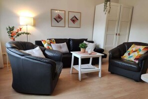 Ein Wohnzimmer mit einer Sofagarnitur, einem Couchtisch und einer Lampe.