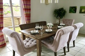 A dining area with a wooden table set for four, surrounded by upholstered chairs. - Holiday home in Sylt with 3 bedrooms (Westerland, Sylt)