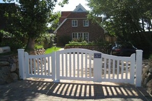 A gated driveway leading to a brick house with a stone wall and a lawn. - Holiday home in Sylt with 3 bedrooms (Westerland, Sylt)