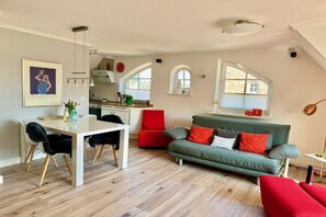 Un espace de vie moderne comprenant un coin repas, un canapé et une cuisine en arrière-plan.