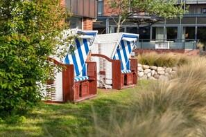 Terrassenstühle mit gestreiften Kissen, ein Backsteinhaus und eine Steinmauer im Hintergrund.
