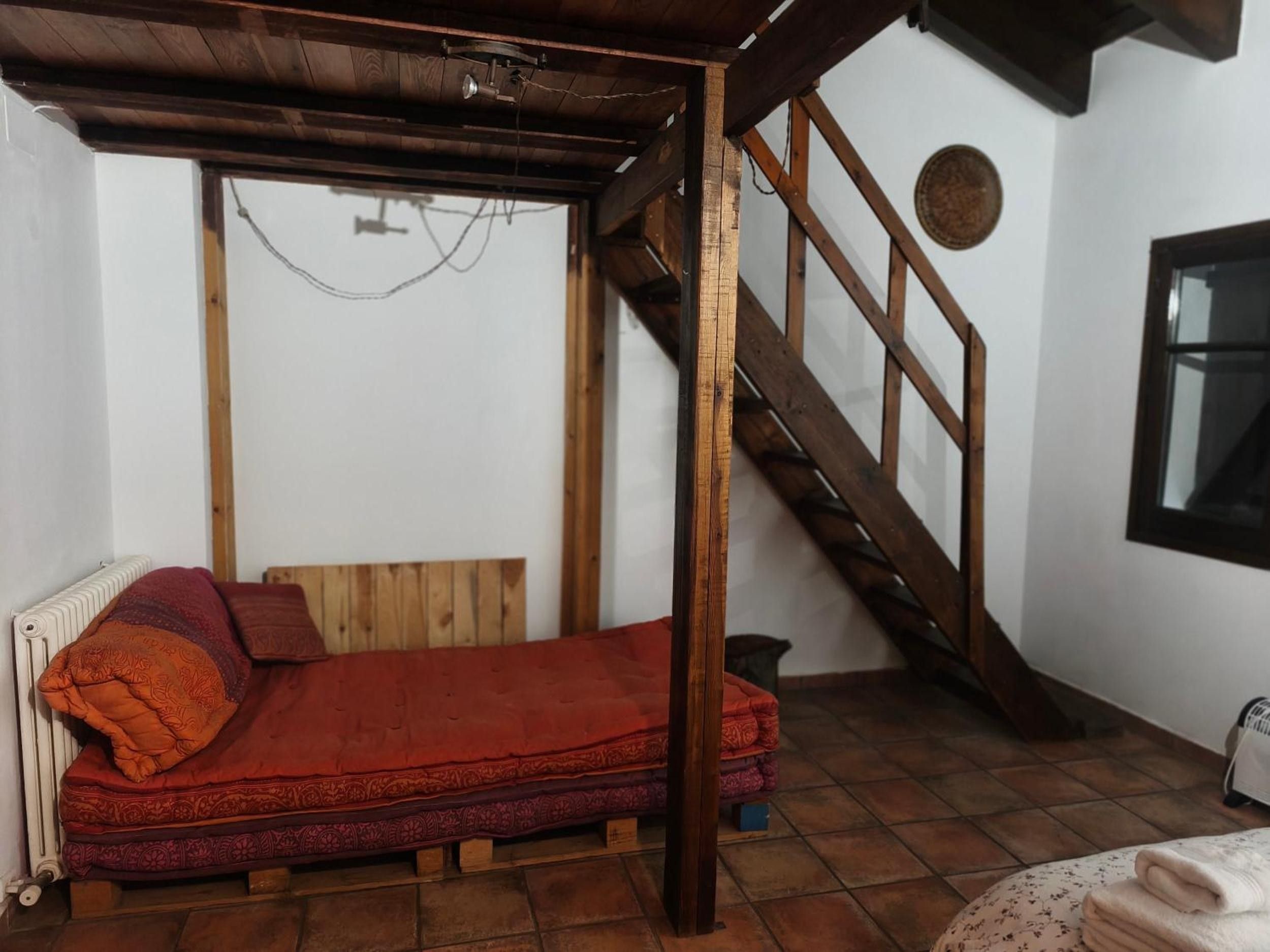 Een kamer met een houten bed, een trap en een radiator.