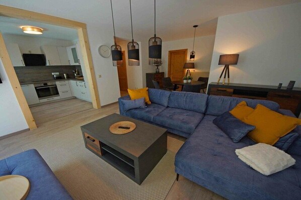 Uma sala de estar moderna com sofá, mesa de centro e área de jantar.
