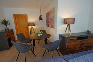 Um espaço de estar moderno com área de jantar, sofá, porta de madeira e radiador.
