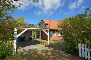 Een gebouw met een overdekte ingang, een bakstenen gevel en een dak met rode tegels.