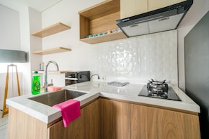 A modern kitchen with a built-in stove, a sink, wooden cabinets, and a backsplash.