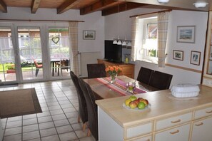 Ein Essbereich mit Tisch, Stühlen, einem Fernseher und einem Fenster mit Vorhängen.