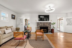 Ein Wohnzimmer mit Kamin, einem darüber hängenden Fernseher und einem Klavier.