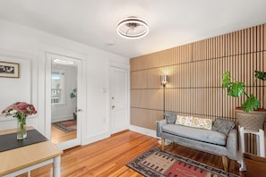 Ein modernes Wohnzimmer mit einer Couch, einem gemusterten Teppich und Holzboden.