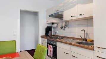 A compact kitchen with white cabinets, a built-in oven, a coffee maker, and a sink.