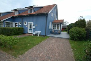 Ein blaues Gebäude mit einem Ziegelweg, der zu einer Bank und einer kleinen Außen-Sitzgelegenheit führt.