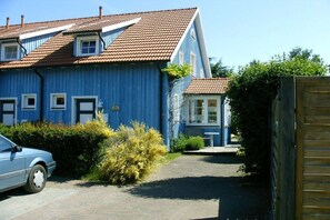 Ein zweistöckiges Haus mit blauer Fassade und rotem Ziegeldach.