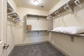 Een kleine, compacte hotelkamer met een stapelbed, een enkel bed met een kussen, een handdoek op het bed en een wandplankje met een handdoek en een klein voorwerp.