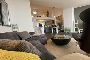 Un saló modern amb un sofà, una taula de centre i una zona de menjador al fons.