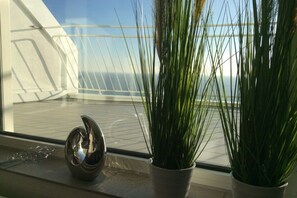 Una planta en test i un objecte esfèric reflectant damunt d'un davantall amb vista a un balcó i un pont.