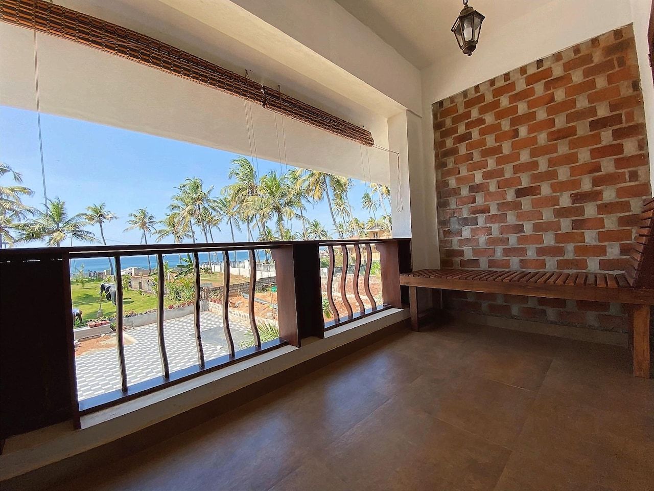 Una habitación con balcón, pared de ladrillo y banco de madera.