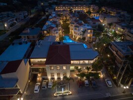 Un hotel de varios pisos con piscina, varios balcones y un estacionamiento.
