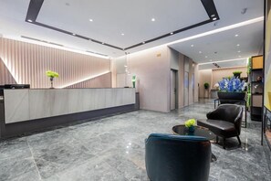 A modern hotel lobby with a reception desk, seating area, and a staircase. - Home inn Selected (Shanghai)