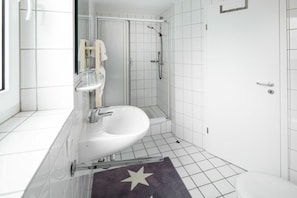 A modern bathroom with a white sink, a glass shower enclosure, and a white toilet. - Apartment in Juist with Wi-Fi and fishing (Juist)