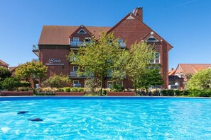 Ein großes Backsteinhaus mit Schwimmbad davor.