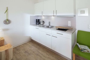 A compact kitchen with white cabinets, a sink, and a coffee maker. - Apartment in Juist with Wi-Fi and fishing (Juist)