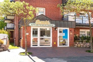 A brick building with a sign reading 'Bracht Appartementhaus' and a glass door entrance. - Apartment in Juist with Wi-Fi and fishing (Juist)