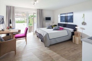 A modern hotel room with a bed, a desk, a chair, a television, and a view of the outdoors. - Apartment in Juist with Wi-Fi and fishing (Juist)