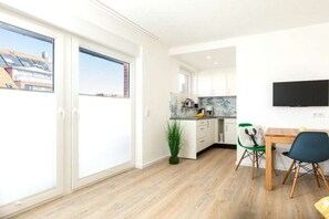 Eine moderne Küche mit Essbereich, einem an der Wand montierten Fernseher und einer Glastür zu einem Außenbereich.