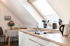 A kitchen with a skylight, a dining table with chairs, and a vase of flowers. - Apartment in Juist with swimming pool (Juist)